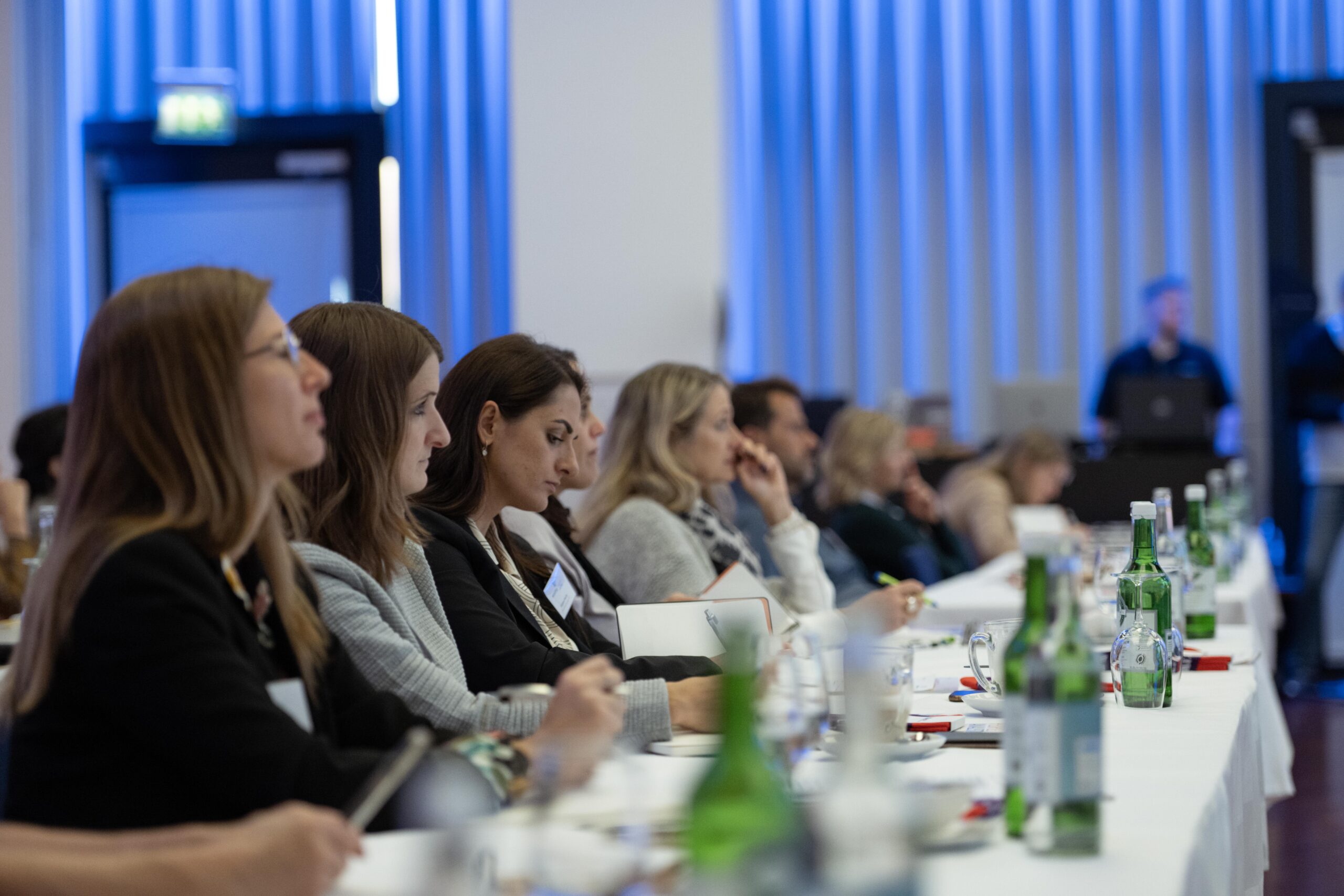 Mehrere Personen die an einem Tisch sitzen und an einem Recruiting Event teilnehmen.