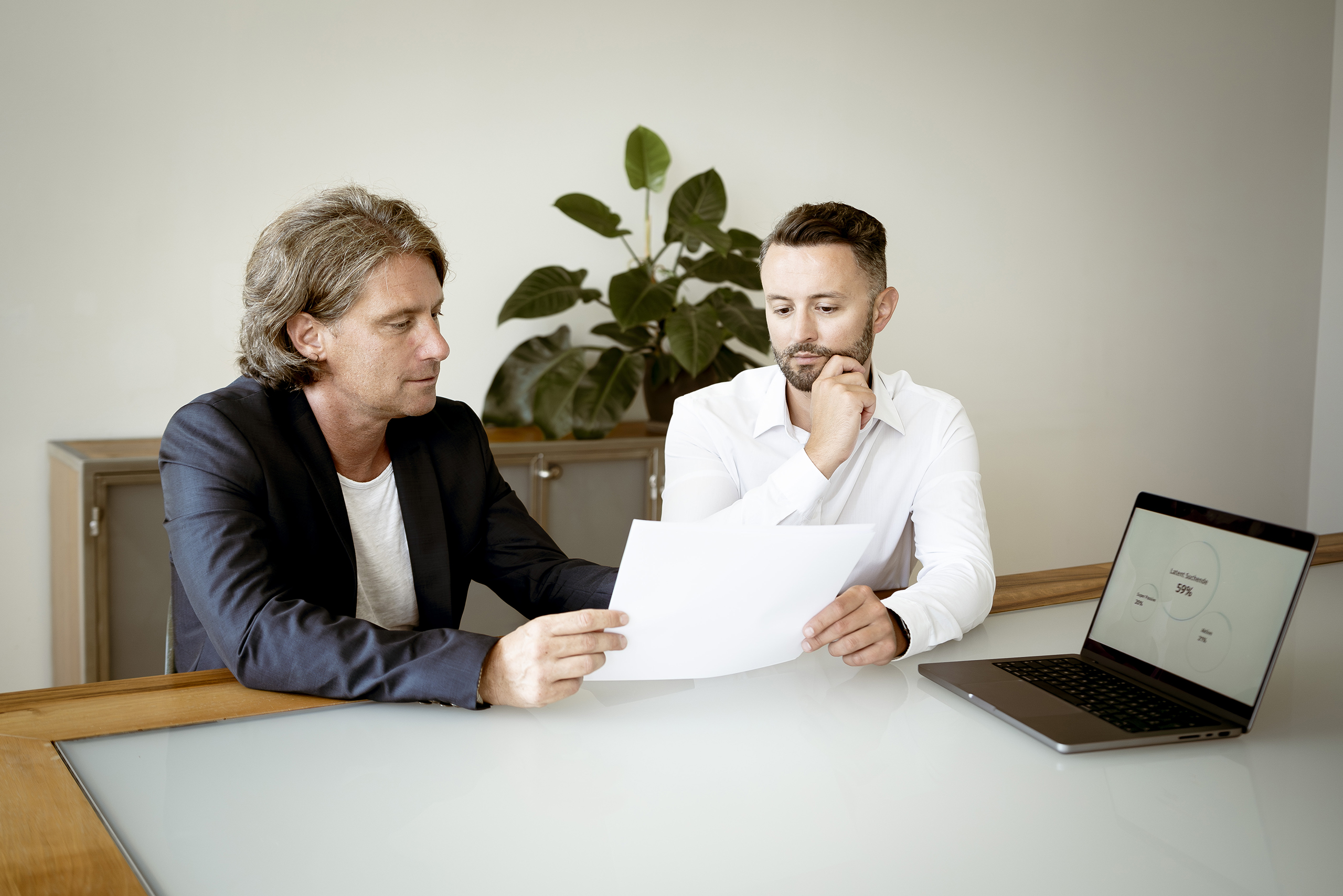 Zwei Männer die an einem Tisch sitzen und Recruiting Studien besprechen